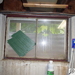 An old, rusted basement window with a steel frame in 7].